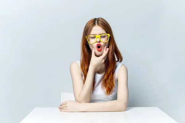 Mujer en gafas amarillas sentada a la mesa sonrisa — Foto de Stock