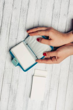 Kadın ellerinde mavi kart tutucu ve beyaz kağıt ahşap arka plan dokusu
