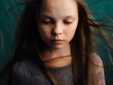 Turkuaz arka planda dağınık saçları olan tatlı küçük bir kız güzel bir yüz.