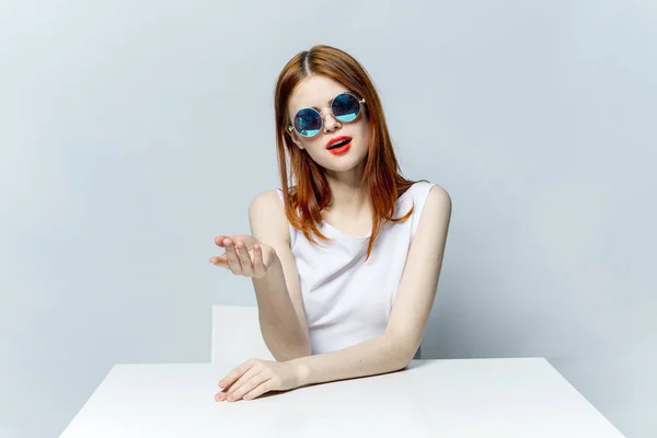 Alegre mulher ruiva sentada à mesa óculos de sol — Fotografia de Stock