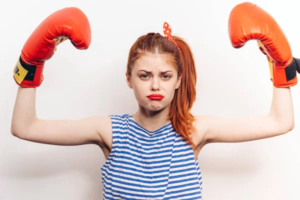 Mujer triste con guantes rojos en un ligero gesto uniforme con las manos y una camiseta a rayas — Foto de Stock