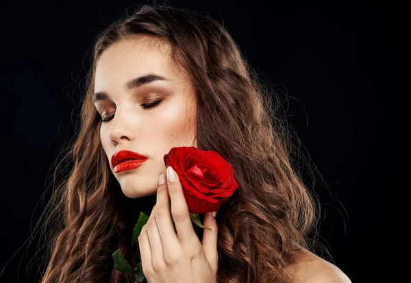 Femme romantique sur fond noir avec fleur rouge dans ses mains — Photo