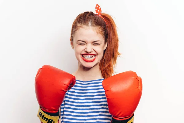 Mujer fuerte en guantes de boxeo rojos y en una camiseta a rayas vista frontal fondo claro — Foto de Stock