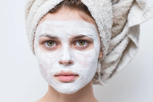 Femme avec une serviette sur la tête et une crème hydratante sur le visage — Photo