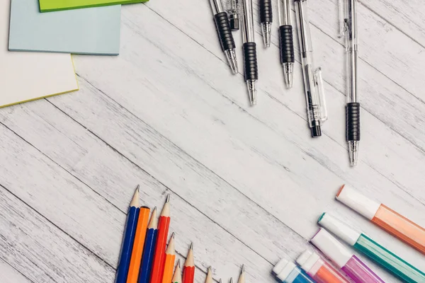 Markerek ceruzák tollak egy fából készült asztalon és színes papírirodai írószerek — Stock Fotó