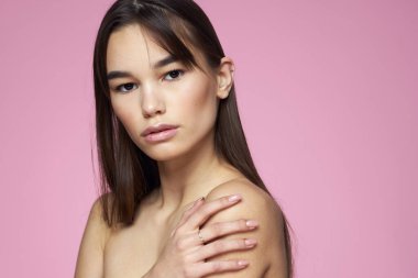 Esmer, çıplak omuzlar, temiz cilt bakımı pembe arka plan.