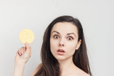 Güzel esmer, çıplak omuzlar, kozmetik ürünleri süngeri.