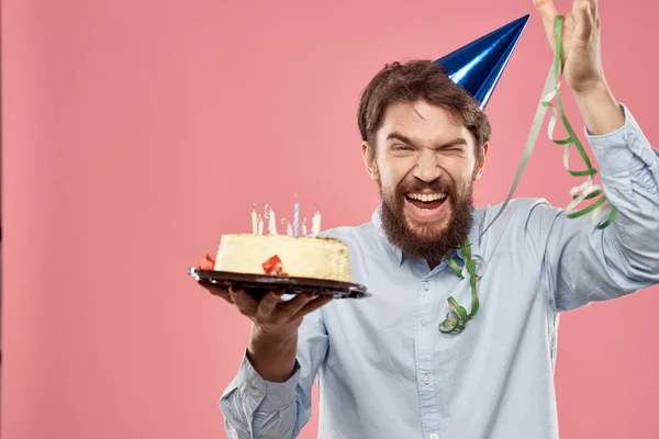 Hombre barbudo con lengua de pastel sobre un fondo rosa vista recortada y una gorra azul en la cabeza — Foto de Stock