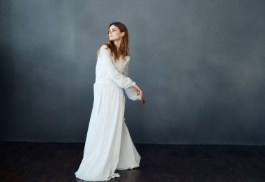 Beyaz elbiseli çekici bir kadının portresi. Gri bir arka planda. Tamamen büyümüş.