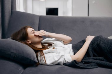 Kanepede uzanmış bir kadın kendini evinde hissetmediği için yüzünü kapatıyor.