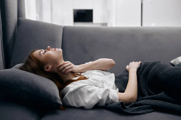 Mujer acostada en el sofá en casa mano en el cuello problemas de salud —  Fotos de Stock