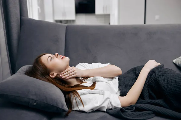 Kobieta leżąca na kanapie z problemami ze zdrowiem szyi w domu — Zdjęcie stockowe
