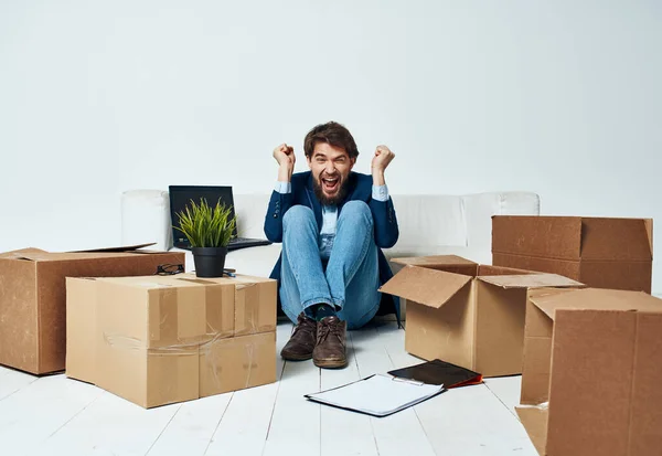 Man sitting on the floor with boxes of stuff moving to office unpacking lifestyle