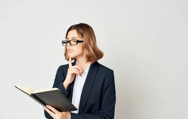 Femme d'affaires dans une veste bleue et une chemise blanche avec des lunettes sur son visage et un livre dans ses mains — Photo