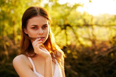 Beyaz elbiseli romantik bir kadın parkta el kol hareketi yapıyor.