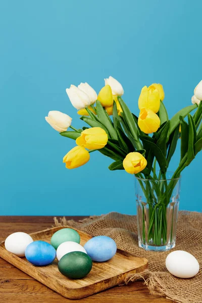 Oeufs de Pâques colorés sur bouquet de table en bois de décoration de fleurs — Photo