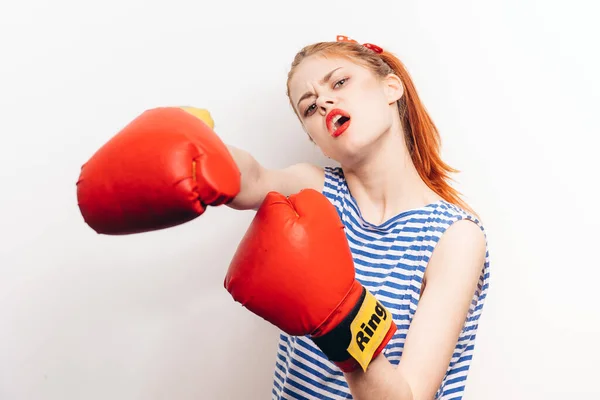 Femme agressive boxe sur un fond clair dans un t-shirt rayé et gants rouges vue recadrée — Photo