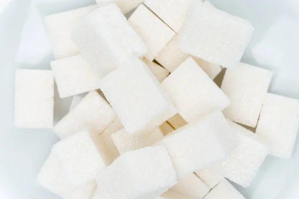 Cubes de sucre granulé sur une assiette bonbons fond clair — Photo