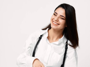 Gömlekli güzel esmer kadın gülüyor ve yan tarafa bakıyor.