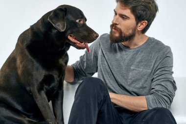 Evdeki adam safkan köpekle kanepede arkadaşça eğleniyor.