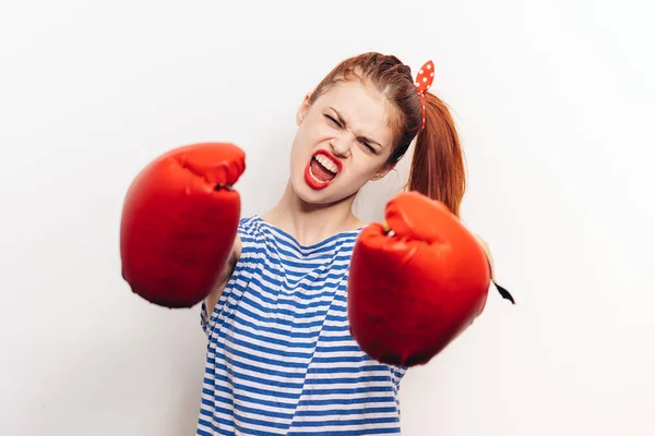 Deportista agresiva en guantes de boxeo y una camiseta a rayas lucha sobre un fondo claro — Foto de Stock