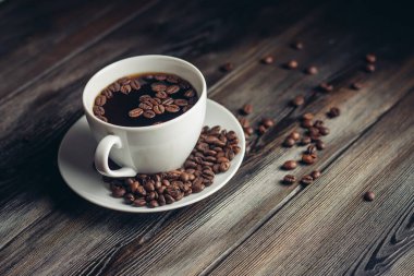 Kahve fincanlarında aromatik içecek, fasulye, ahşap masa kahvaltısı.