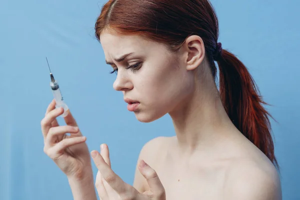 Женщина держит шприц возле лица ботокс омоложения инъекции синий фон — стоковое фото