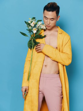 Mavi arka planda düğmesiz sarı ceketli seksi adam.