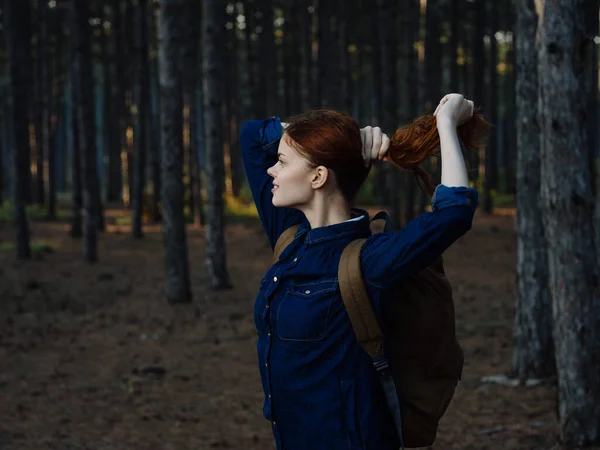 Mulher sem camisa de cabelos vermelhos com uma mochila nas costas descansando em uma floresta de pinheiros e vista cortada — Fotografia de Stock