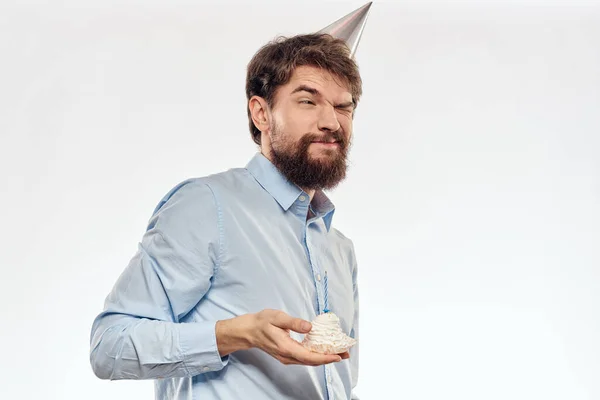 Мужчина с бородой держит в руке торт на светлом фоне дня рождения — стоковое фото
