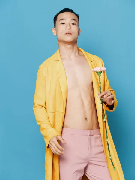 Korean man in a yellow coat with a flower in his hand and pink trousers — Stock Photo, Image