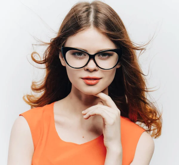 Hübsche Frau in orangefarbenem Kleid und Brille auf hellem Hintergrund — Stockfoto