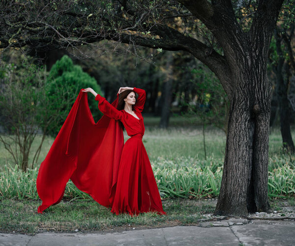 Woman in red dress charm nature tree luxury posing. High quality photo