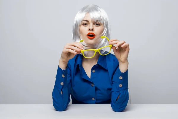 Alegre bonita mujer en un blanco peluca se sienta a la mesa rojo labios encanto amarillo gafas — Foto de Stock