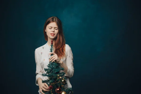 Kvinna med en julgran i handen på en blå bakgrund och runda bollar leksaker nyår — Stockfoto
