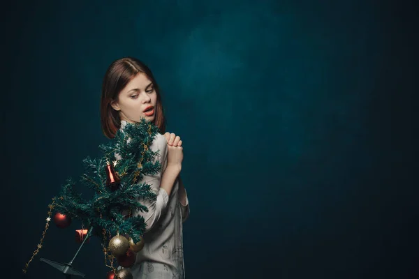 Kvinna med en julgran i handen på en blå bakgrund och runda bollar leksaker nyår — Stockfoto