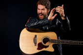 Muž s kytarou v ruce kožené sako hudební výkon rocková hvězda moderní styl tmavé pozadí