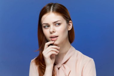 Pembe gömlekli güzel bir kadın elleri mavi arka planda.