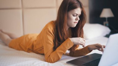 Kadın dizüstü bilgisayarın önünde yatıyor. Teknoloji serbest çalışıyor.