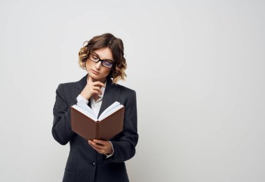 İş kadını elinde bir kitapla arka planı aydınlık görünüyor. Bulmaca gibi görünüyor.