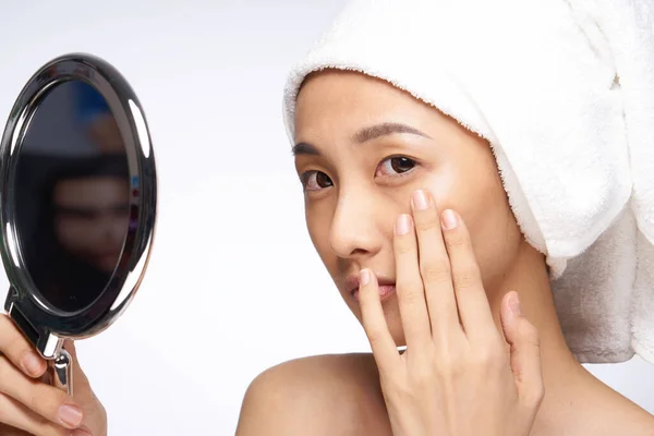 asian woman touching hand face mirror in hands skin care