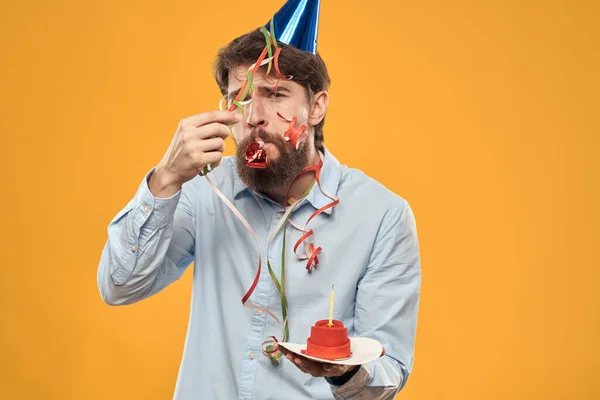 Chico con un pastel en un plato en un fondo amarillo vacaciones vela vista recortada — Foto de Stock