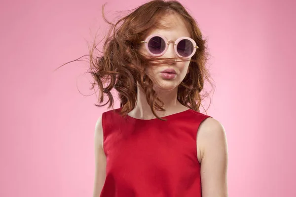 Chica con pelo rizado gafas de sol alegría infantil fondo rosa — Foto de Stock