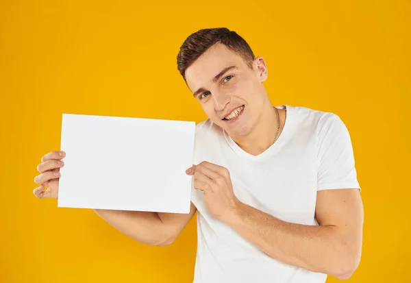 Homme avec maquette feuille blanche de papier carte de visite d'affaires fond jaune — Photo