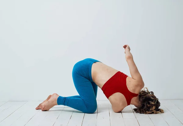 Una mujer se arrodilla en el suelo con el brazo doblado y ejercicios de yoga asana — Foto de Stock