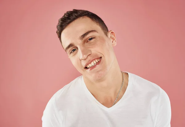 Porträtt av en glad kille på en rosa bakgrund beskärs utsikt över en vit t-shirt känslor — Stockfoto