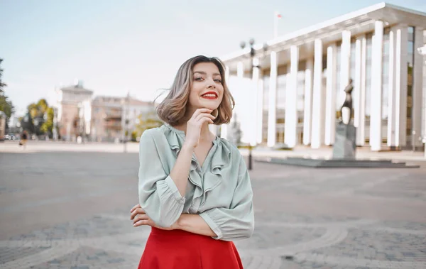 Женщина в юбке в рубашке прогуливается по центральным улицам города и высоким зданиям на заднем плане — стоковое фото