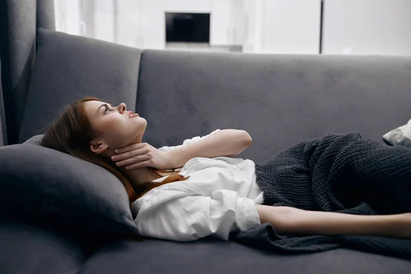 Kobieta leżąca na kanapie ręka w szyję źle się czując problemy zdrowotne — Zdjęcie stockowe