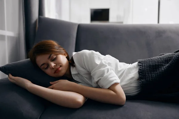 Beyaz tişörtlü kadın gri kanepede yatıyor. Yakın plan çekilmiş. — Stok fotoğraf