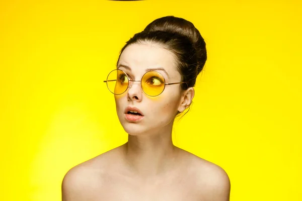 Emocional morena nu ombros reunidos cabelo em um fundo amarelo coque — Fotografia de Stock